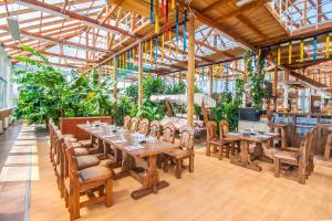 un restaurante con mesas de madera, sillas y plantas en Agrousadba Abuzerye, en Abuzierje