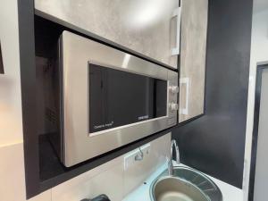 a microwave oven above a sink in a bathroom at Апартаменты в Аркадии - Arcadia Sky Apartments in Odesa