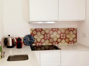 eine Küchentheke mit Spüle und Uhr in der Unterkunft Luisa's Loft in Setúbal