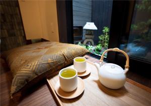 2 tazas de té en una mesa de madera junto a una cama en 谷町君・星屋・城下の宿 en Kioto