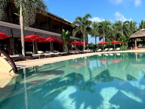 uma grande piscina com guarda-sóis vermelhos num resort em The Island Lodge em Mỹ Tho