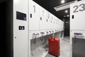 a red suitcase is sitting in a locker room at HOTEL TAVINOS Hamamatsucho in Tokyo