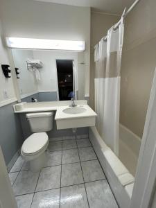 
a bathroom with a toilet, sink, and shower at Hollywood Guest Inn in Los Angeles
