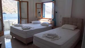 two beds in a room with two windows at Sifis in Loutro