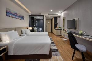 Habitación de hotel con 2 camas, escritorio y TV. en Khách sạn SAM Quảng Bình en Ðồng Hới