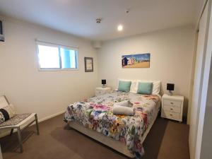 a bedroom with a bed and a chair and a window at Marina Park Apartments Whitianga in Whitianga