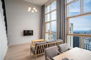 a living room with a couch and a table and windows at Jeju Central Park Residence in Jeju