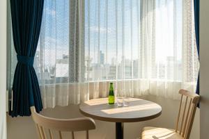東京的住宿－BON Tokyo Asakusa，窗户前的桌子和一瓶葡萄酒