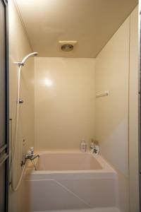 a white bath tub in a bathroom with a shower at Guesthouse EN in Rusutsu