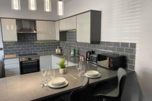 a kitchen with a table with plates and wine glasses at The Garden Apartment with Hot Tub - Westbrook Bay Beach - By Goldex Coastal Breaks in Kent