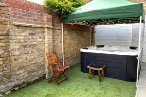 a hot tub and two chairs under a green umbrella at The Garden Apartment with Hot Tub - Westbrook Bay Beach - By Goldex Coastal Breaks in Kent