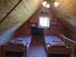 two beds in a attic room with a window at Domek Wałacha in Istebna