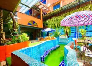 a swimming pool in a building with tables and umbrellas at 4J Lodge in Bangkok