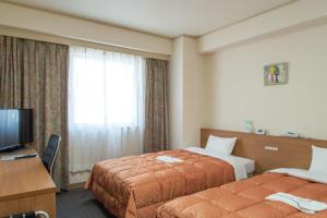 a hotel room with two beds and a television at Hotel Maira in Okayama