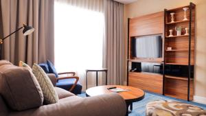 a living room with a couch and a television at Mercure Jakarta Cikini in Jakarta