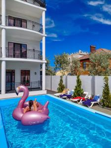 a woman is riding on a pink swan in a swimming pool at Villa Bonapart in Zatoka