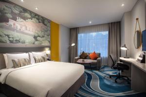 ジャカルタにあるメルキュール ジャカルタ チキニの大きなベッドとデスクが備わるホテルルームです。