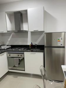 a kitchen with white cabinets and stainless steel appliances at Asuncion Gracia Suites in Asuncion