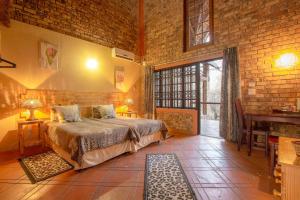 1 dormitorio con cama y pared de ladrillo en SERENITY Du Bois Lodge, en Marloth Park