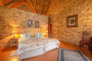 a bedroom with a bed in a brick wall at SERENITY Du Bois Lodge in Marloth Park