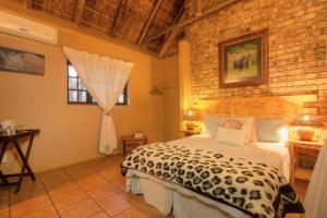 a bedroom with a bed and a brick wall at SERENITY Du Bois Lodge in Marloth Park