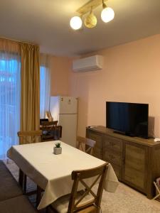 a living room with a table and a flat screen tv at Mirabell Apartment Bansko - Mountain View & Fireplace in Bansko