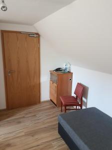 a room with a bed and a wooden door and a chair at Pension Zur Eiche in Drebenstedt
