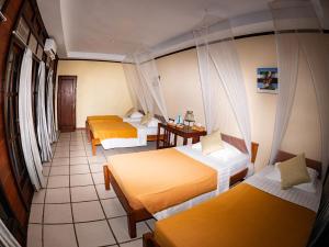 ein Hotelzimmer mit 3 Betten und einem Tisch in der Unterkunft Waiwo Dive Resort Raja Ampat in Rabia