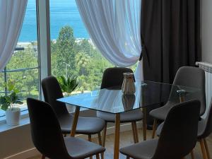 einen Tisch und Stühle in einem Zimmer mit einem großen Fenster in der Unterkunft Maia's Sweet Homes in Batumi