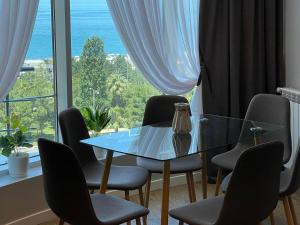 a table and chairs in a room with a large window at Maia's Sweet Homes in Batumi