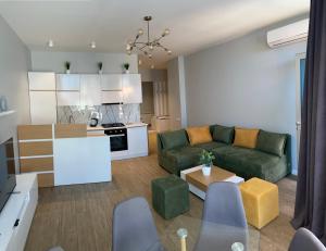 a living room with a green couch and a kitchen at Maia's Sweet Homes in Batumi