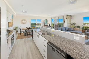 a kitchen with a counter top and a living room at Pelican Waters Resort in Caloundra