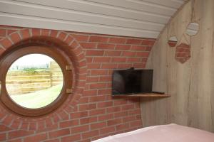 Habitación con pared de ladrillo, TV y ventana. en Wabbit, The Little Burrow, Radstock, en Radstock