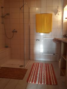 baño con ducha y alfombra roja y blanca en Komfortzimmer Haus Dervaritz, en Einöd