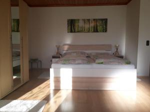 een slaapkamer met een groot wit bed en een spiegel bij Komfortzimmer Haus Dervaritz in Einöd
