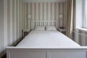 - un lit blanc dans une chambre avec deux tables dans l'établissement Cosy Scandi Home near the Old Town. Self Check-In, à Klaipėda