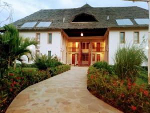 a large white house with a walkway at The Last Village Lodge in Athi River