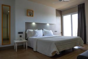 a bedroom with a large white bed with a window at Hotel MC San José in San José
