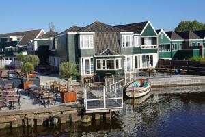 un groupe de maisons avec un bateau dans l'eau dans l'établissement Boutique Hotel Zaan, à Zaandijk