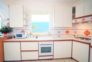 a kitchen with white cabinets and a window at La Casetta delle Api in Capri +15 photos