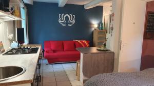 a living room with a red couch and a kitchen at les floralis studio in La Grée-Saint-Laurent