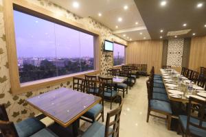 a restaurant with tables and chairs and a large window at Nilay Residency in Bhubaneshwar