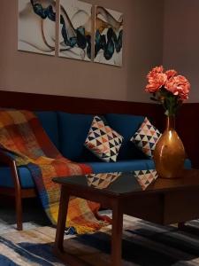 a blue couch with a table and a vase with flowers at Biz Hotel Apartments in Tabuk