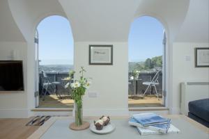 Una sala de estar con un jarrón de flores sobre una mesa. en Waterview House, Kingswear, en Kingswear