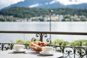 un tavolo con una ciotola di croissant e due tazze sul balcone di Hotel Seeburg a Lucerna