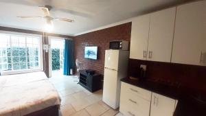 a bedroom with a bed and a white refrigerator at Cozy Hatfield Condo in Pretoria