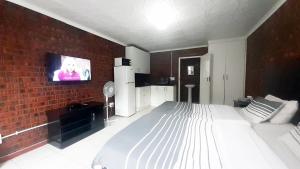 a bedroom with a bed and a tv on a brick wall at Cozy Hatfield Condo in Pretoria