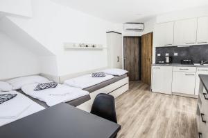 a room with two beds and a table and a kitchen at Hotel U Pláže in Vranov nad Dyjí