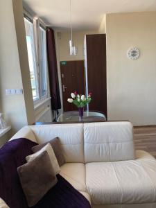 a white couch in a living room with a vase of flowers at Apartman HIGHTATRAS VIEW Centrum Poprad in Poprad