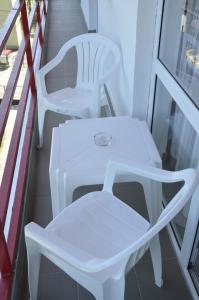 dwa białe krzesła i stół na balkonie w obiekcie Vila Iunona w mieście Costinesti